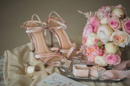 Beige shoes of the bride , rings and a bouquet of flowers .の写真素材