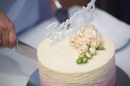 Beautiful wedding cake with flowers. The bride cuts the cake.の写真素材