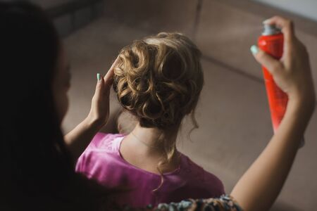 Master stylist makes the bride wedding hairstyle using spray lacquer fixing.