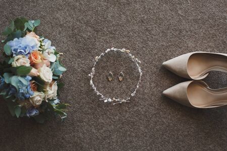 Tender beige wedding shoes and earrings and a wedding bouquet.の写真素材