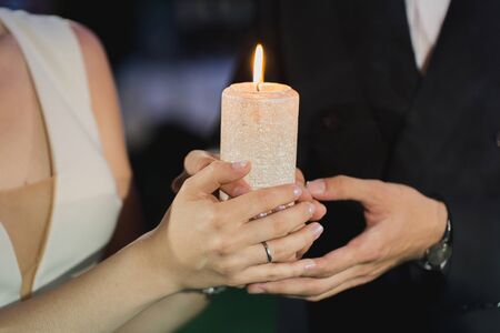 bride and groom hold a candle in their hands.の写真素材