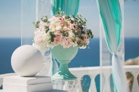 Wedding arch for the ceremony and a vase with wedding flowers, against the background of the seaの写真素材