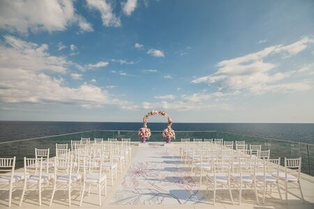 Wedding arch with fresh flowers on a sea background. Vases with fresh flowersの写真素材