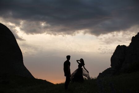 Silhouettes of a young couple lovers at sunset in rays of setting sun.の写真素材