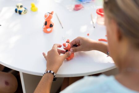 Childrens hands are molded from plasticine on a white table.