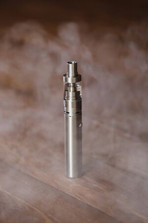 Electronic cigarette on a wooden table. Smoke.