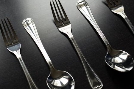 Silver Cutlery on a black table background.の写真素材