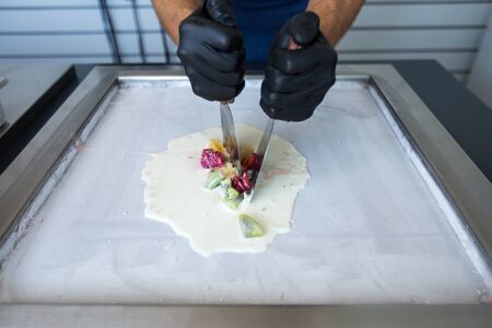 Stir-fried ice cream rolls at freeze pan. Rolled ice cream, hand made ice cream dessert. Fried ice cream machine with steel chilled pan.の写真素材