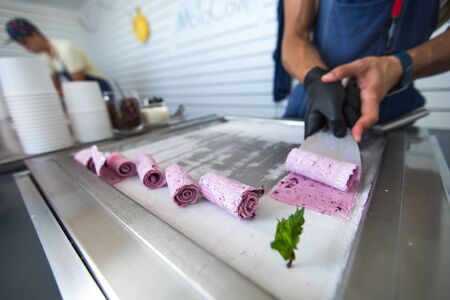 Stir-fried ice cream rolls at freeze pan. Rolled ice cream, hand made ice cream dessert. Fried ice cream machine with steel chilled pan.の写真素材