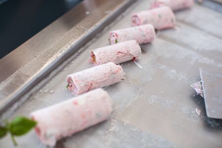 Stir-fried ice cream rolls at freeze pan. Rolled ice cream, hand made ice cream dessert. Fried ice cream machine with steel chilled pan.の写真素材