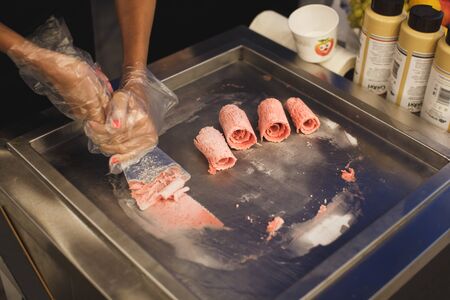 Stir-fried ice cream rolls at freeze pan. Rolled ice cream, hand made ice cream dessert. Stir-fried ice-cream from milk and berry jam. Fried ice cream machine with steel chilled pan.の写真素材