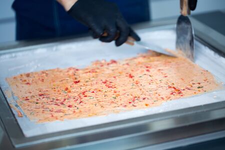 Stir-fried ice cream rolls at freeze pan. Rolled ice cream, hand made ice cream dessert. Fried ice cream machine with steel chilled pan.の写真素材