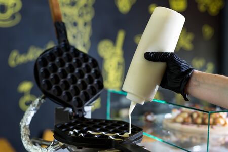 Pouring dough on waffle maker. Preparing Hong Kong waffle