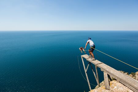 Rope jumping off a cliff with a rope in the water. The ocean. Sea. Mountain.の写真素材