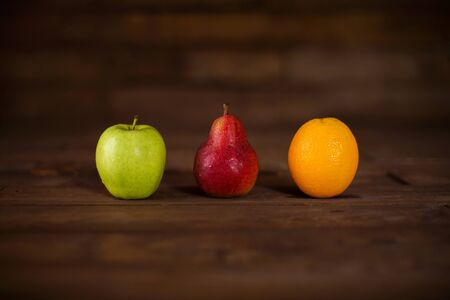 Apple, pear and orange on a wooden table
