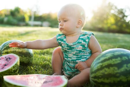 Little boy with a watermelon sitting on the grassの写真素材