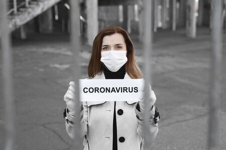 A woman behind bars in isolation holds a placard reading coronavirus . Message for the prevention of coronavirus covind-19の写真素材