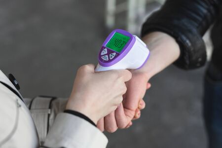Operator check fever by digital thermometer visitor at information counter for scan and protect from coronavirus COVID-19の写真素材