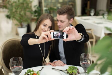 Beautiful couple taking selfie photo in a restaurant.の写真素材