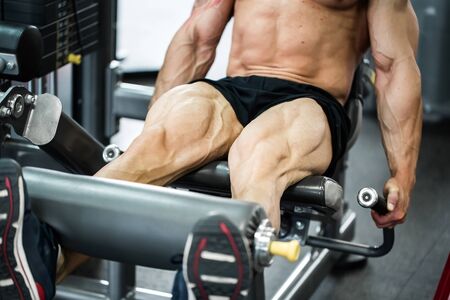 Gym fitness club indoor with young man training weights with legs.の写真素材