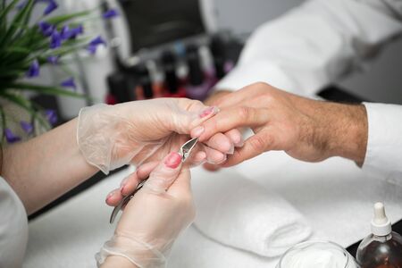 Close-up Of A Manicurist Cutting Off The Cuticle From The Person's Fingersの写真素材