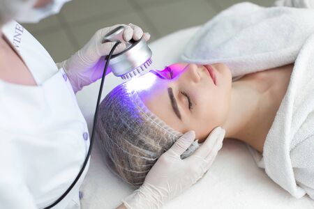 Ultrasonic massager. Light skin treatment, the woman in the beauty salon