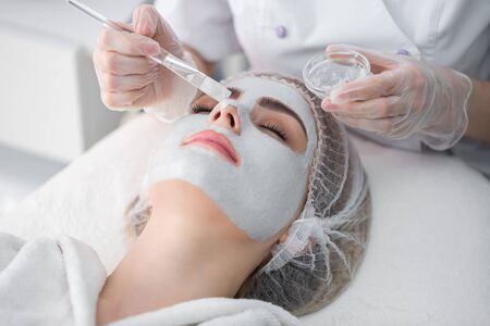 Face peeling mask, spa beauty treatment, skincare. Woman getting facial care by beautician at spa...