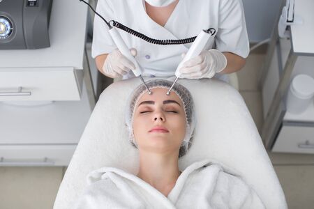 Macro close up portrait of woman having cosmetic galvanic beauty treatment in spa.Therapist applying...