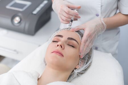 Woman gets injection in her face. Beauty woman giving botox injections. Young woman gets beauty...