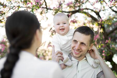 Happy man and woman playing with baby outdoors.