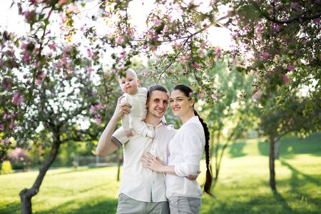 Portrait of a young family with a child. Happy young family spending time outdoor on a summer day. Happiness and harmony in family life. Happy family conceptの写真素材