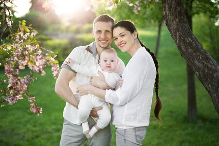 Portrait of a young family with a child. Happy young family spending time outdoor on a summer day. Happiness and harmony in family life. Happy family conceptの写真素材