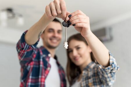 Couple showing keys to new home. Happy young couple moving together in new apartment.の写真素材