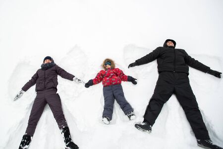 A happy family lies in the snow in winter.の写真素材