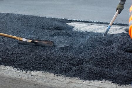 The road workers working group updates part of the road with fresh hot asphalt and smoothes it for repair.の写真素材