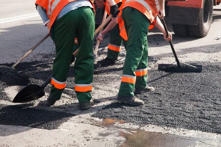 Workers on Asphalting paver machine during Road street repairing works. Street resurfacing. Fresh...