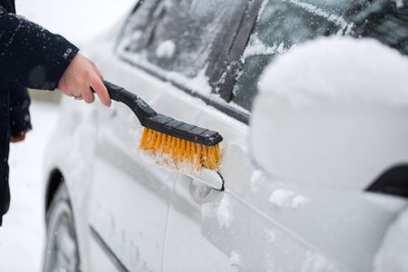 Woman cleaning snow from the car in the winter. Car handle.