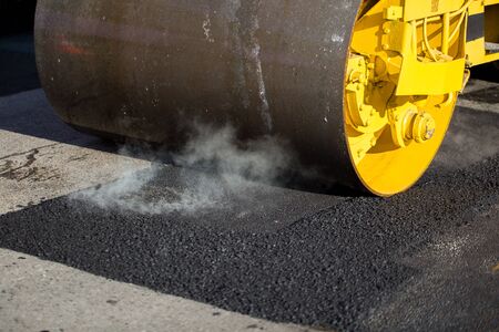 Road roller compacting asphalt during road repairs
