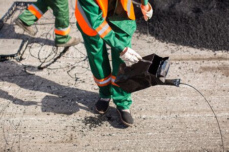 The man working asphalt pouring tar for road repair.の写真素材