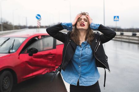Woman stands near a broken car after an accident. call for help. car insurance.の写真素材