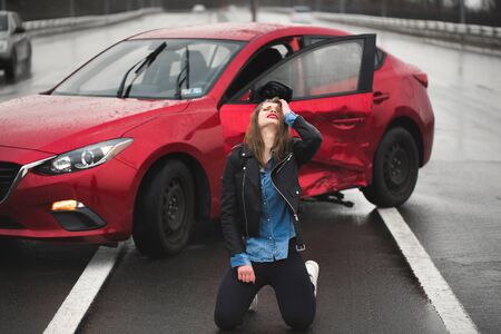 Woman sitting on the road after an accident. Injured woman feeling bad after having a car crash.