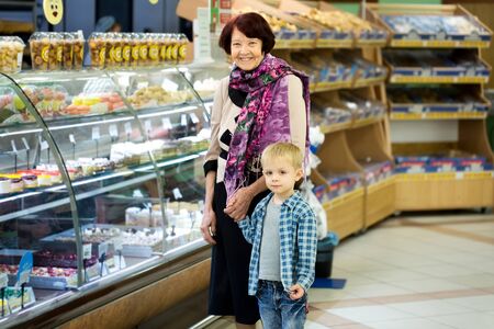 Adult woman with child choosing dessert while shopping in supermarket.の写真素材