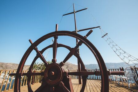 Rudder of an old wooden sailing boat. Steering wheel of a retro vintage ship.の写真素材