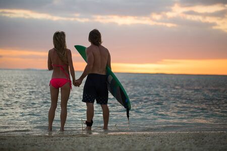 Man and a Woman with Surf Boards at Sunset