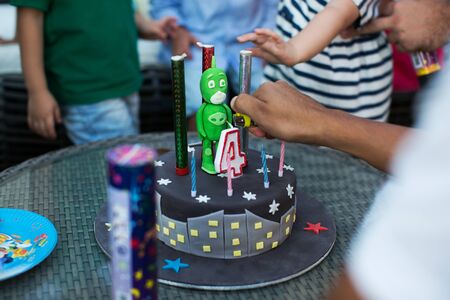 Kids birthday party. Child blowing out candles on colorful cake.の写真素材