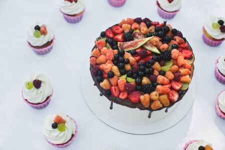 Delicious fruit cake with cupcakes for a happy birthday.