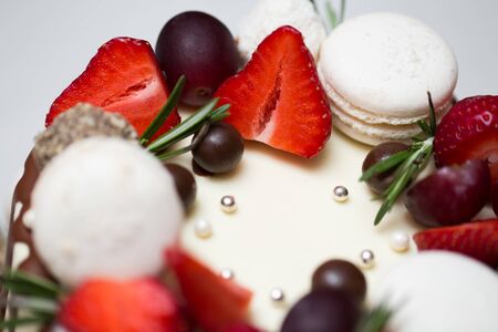 Cake with chocolate drips, strawberries, peaches, macaroons, rosemary.の写真素材