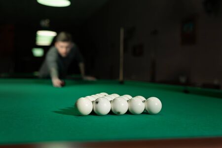 Game of billiards. The man puts the balls on the green billiard table