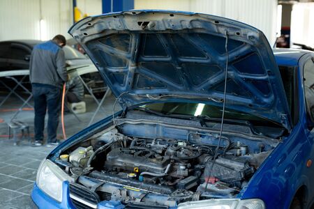 A car with an open hood in service.