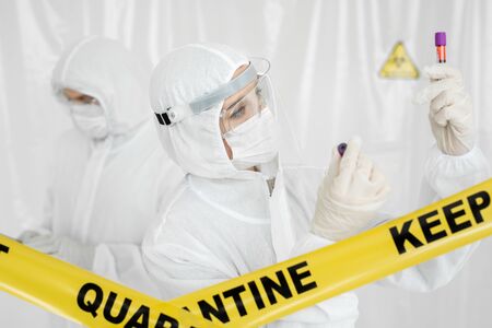 Coronavirus Covid 19 infected blood sample in sample tube in hand of scientist doctor biohazard protection clothing in coronavirus covid 19 research laboratory, Coronavirus Covid-19 vaccine researchの写真素材